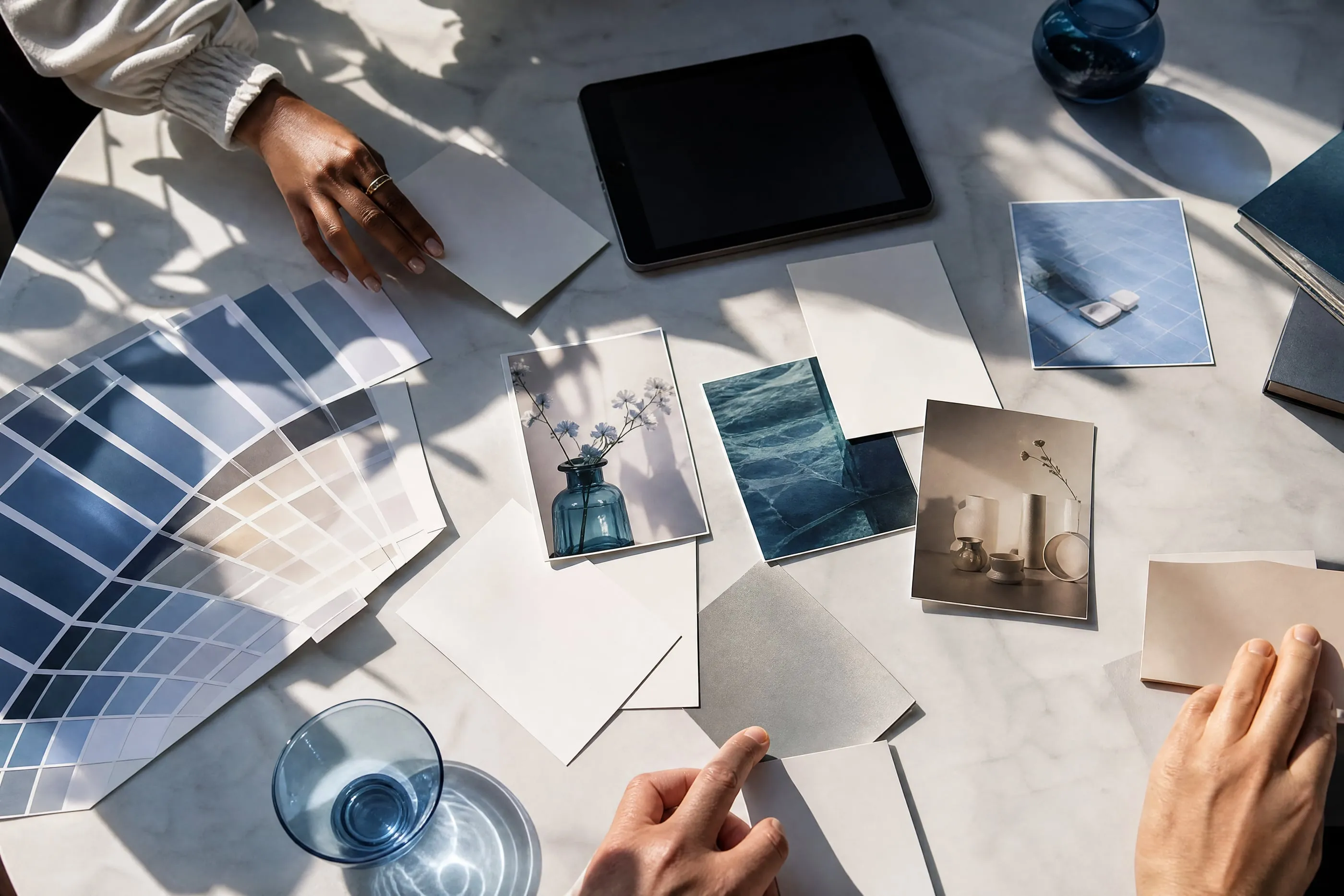 Mesa de trabajo con muestras de color, fotografías de producto y una tableta, vista desde arriba